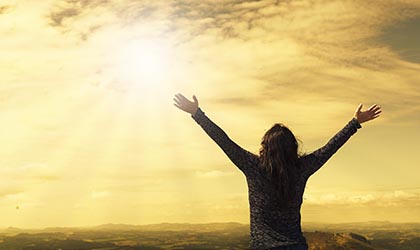 Frau streckt die Arme zur Sonne