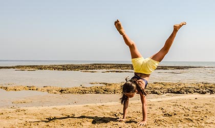 Mächchen schlägt das Rad am Strand