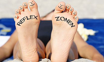 Ein paar Fusssohlen, links steht Reflex und rechts Zonen